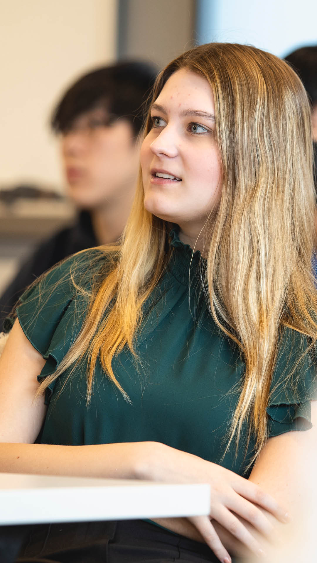 Girl smiling with hands crossed in class